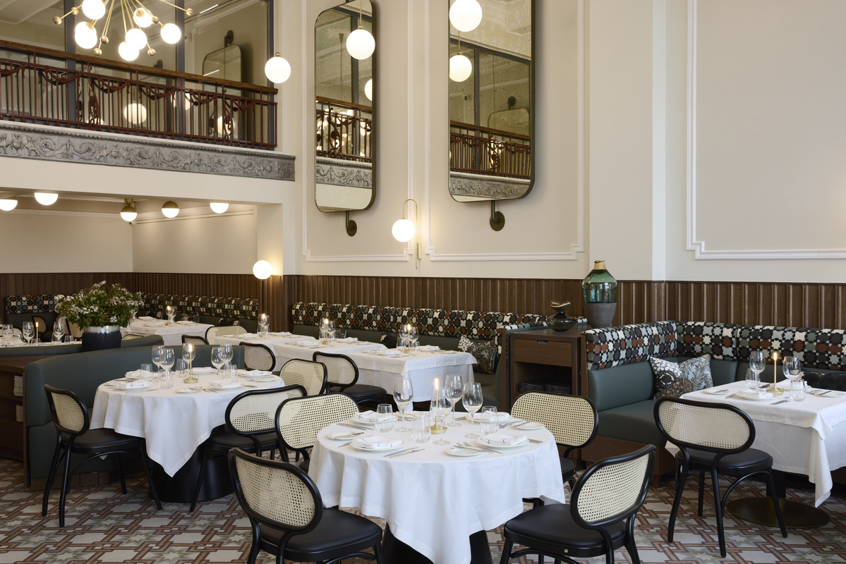 Refined dining room at Olympos Naoussa restaurant with round tables, art deco mirrors, and elegant lighting