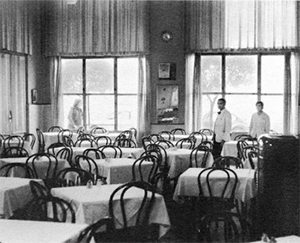 Vintage dining hall of Olympos Naoussa restaurant with set tables and waiters