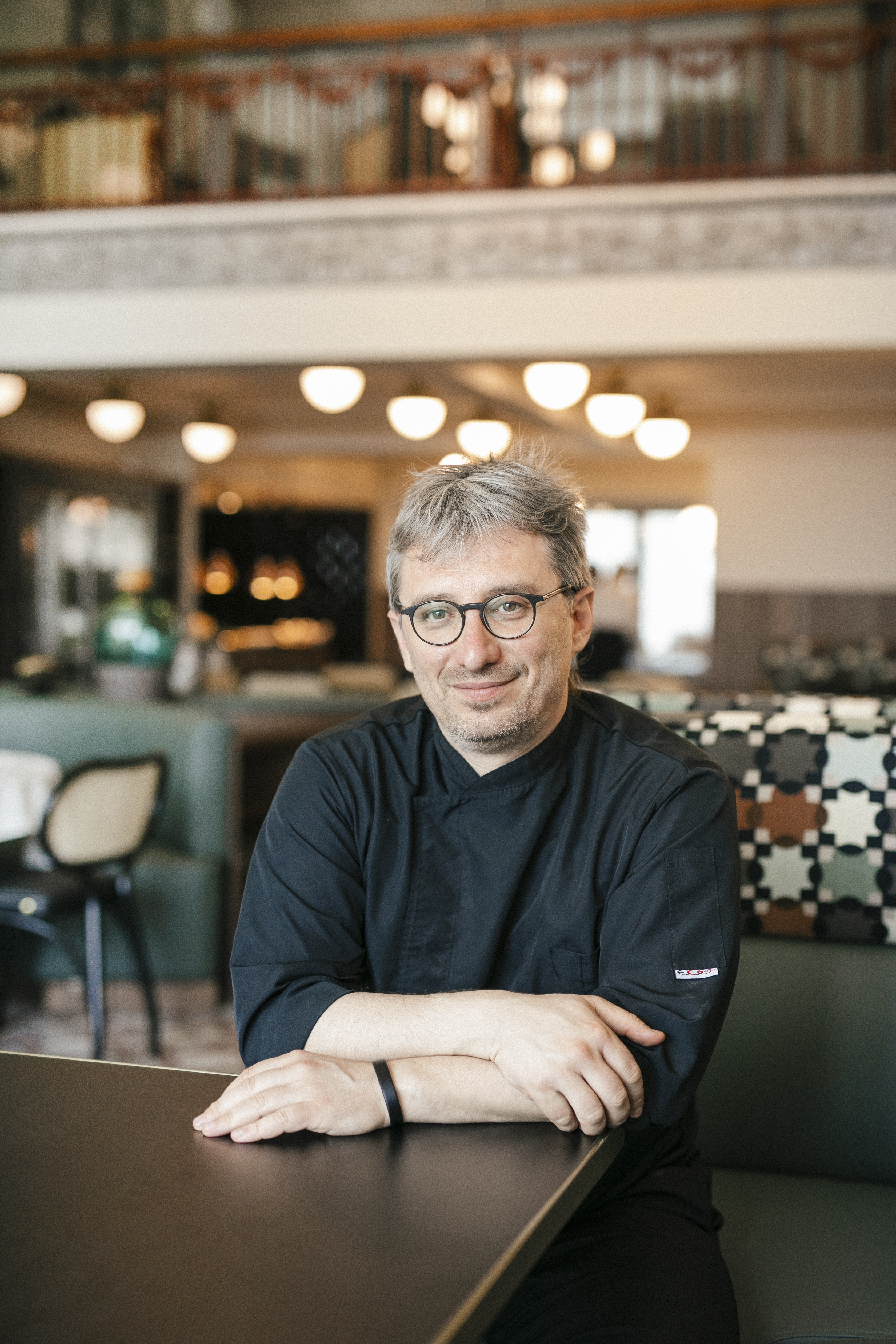 Chef seated in Olympos Naoussa restaurant dining area wearing black uniform