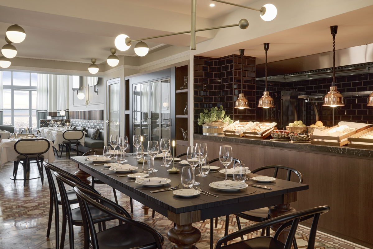 Modern dining area in Olympos Naoussa restaurant with set table, open kitchen, and stylish lighting